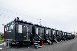 une rangée de remorques noires garées sur le côté d’une route dans l'établissement HOTEL R9 The Yard Hitachinakaichige, à Hitachinaka