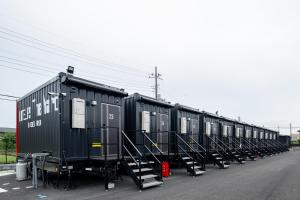a row of black trailers parked on the side of a road at HOTEL R9 The Yard Hitachinakaichige in Hitachinaka
