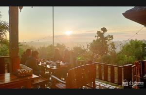 a group of people sitting at a table watching the sunset at Baandindon Private Earthhouse Homestay in Mae Rim