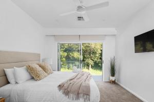 a white bedroom with a large bed and a window at HideAwayII at Shoal Bay in Shoal Bay