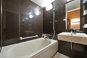 Wakayama Urban Hotel في واكاياما: حمام مع حوض أبيض ومغسلة