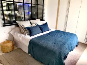 Schlafzimmer mit einem Bett mit blauer Bettwäsche und einem Fenster in der Unterkunft Villa Couloubrier in Sainte-Maxime