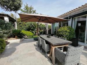 einen Holztisch mit Stühlen und einem Sonnenschirm auf einer Terrasse in der Unterkunft Villa Couloubrier in Sainte-Maxime