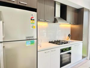 Una cocina blanca con refrigerador y estufa. en Austral Newly Built Modern 3 Br Home, en Horningsea Park