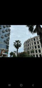 a tall building with a palm tree in front of it at Orbi Sea Towers in Batumi