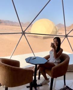 a woman sitting in a chair in the desert at Katrina Rum camp in Wadi Rum