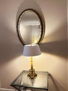 a lamp on a glass table with a mirror at Luxe 3BR, 2BA + Hot Tub in Elmhurst