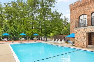 a swimming pool with chairs and umbrellas next to a brick building at Sheraton Nashua in Nashua