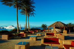 Hurghada Marriott Beach Resort في الغردقة: منتجع به طاولات و نخيل و قارب