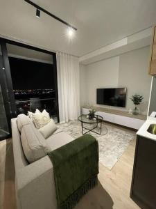 Il comprend un salon doté d'un canapé et d'une télévision à écran plat. dans l'établissement Ellipse Waterfall luxurious unit, à Midrand