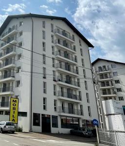 ein großes weißes Gebäude mit davor geparkten Autos in der Unterkunft Apartament - Housing21 in Gura Humorului