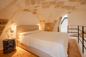 1 dormitorio con 1 cama blanca en una pared de piedra en le CASINE di MARUGGIO 10, en Maruggio