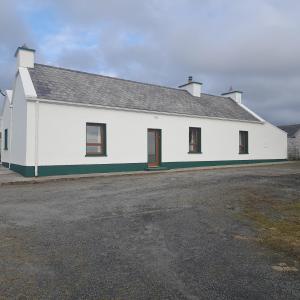 un edificio blanco con techo negro en Biddys cottage, en Donegal