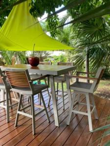 ein Tisch und Stühle auf einer Terrasse mit einem gelben Sonnenschirm in der Unterkunft Villa Ma Vie La in Saint-François