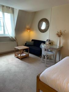 a bedroom with a blue couch and a table at Hotel Des Falaises in Villers-sur-Mer