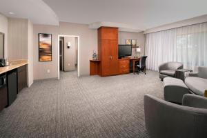 a hotel room with a couch and a desk and a television at Courtyard by Marriott Lufkin in Lufkin