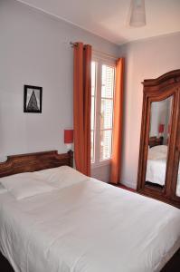 um quarto com uma grande cama branca e um espelho em Hôtel Verlaine em Paris