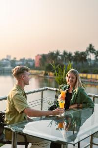 un hombre y una mujer sentados en una mesa con bebidas en Jashore IT Park Hotel and Resort, en Jessore