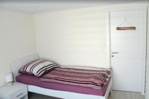 a small bedroom with a bed and a white wall at Eckis Hus in Garding