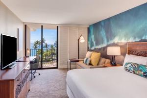 a hotel room with a bed and a desk with a television at Courtyard by Marriott King Kamehameha's Kona Beach Hotel in Kailua-Kona
