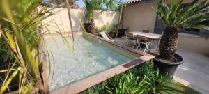 - une petite piscine avec une table et des palmiers dans l'établissement Larimar Etablissement- 200 M de la mer, à Sainte-Maxime
