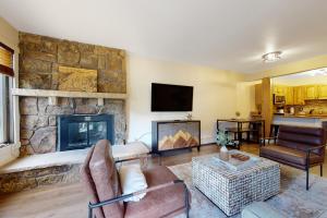 a living room with a fireplace and a stone wall at The Copperado at Copper Valley in Copper Mountain