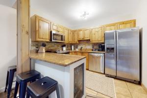 a kitchen with wooden cabinets and a stainless steel refrigerator at The Copperado at Copper Valley in Copper Mountain