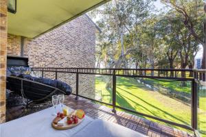 a room with a balcony with a table and a view at Bay Parklands 27 2 Gowrie Ave pool tennis court spa and views in Nelson Bay