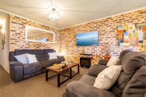 una sala de estar con 2 sofás y una pared de ladrillo en Bay Parklands 27 2 Gowrie Ave pool tennis court spa and views, en Nelson Bay