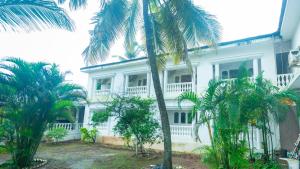 a white building with palm trees in front of it at Lillywoods NV Beach Resort in Calangute