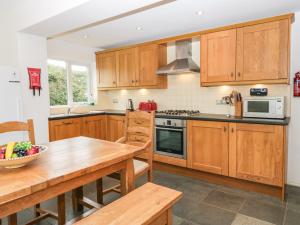 a kitchen with wooden cabinets and a wooden table at Bay View Cottage in Grange Over Sands