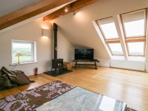 an attic living room with a fireplace and a tv at Bay View Cottage in Grange Over Sands