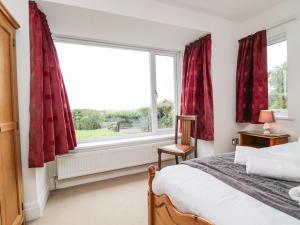 a bedroom with a large window with red curtains at Bay View Cottage in Grange Over Sands