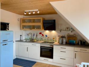 a kitchen with white cabinets and a blue refrigerator at Ferienwohnung Kapellenweg Bambergen bei Überlingen in Bambergen