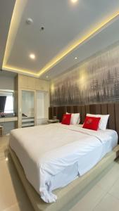 a bedroom with a large white bed with red pillows at Solo Grand City in Lawean
