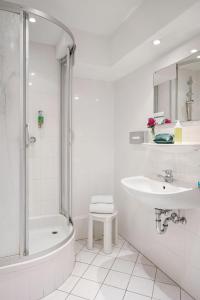 a white bathroom with a tub and a sink and a shower at Styles Hotel Unterföhring in Munich