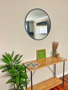 a mirror hanging on a wall above a table with a plant at Quiet & Quaint apartment, 5 mins to airport and 15 mins to downtown in Atlanta