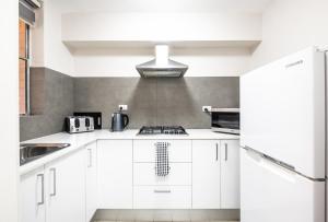 cocina blanca con fregadero y fogones en Central location 2 bdrm free parking and WiFi, en Perth