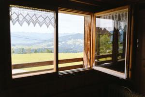 a window with a view of a field and mountains at Haus Berchtold am Hüttersberg in Doren