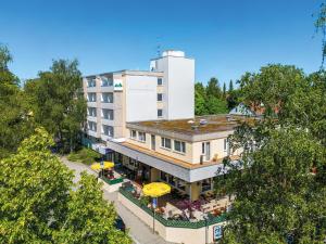 widok na hotel ze stołami i parasolami w obiekcie Styles Hotel Unterföhring w Monachium