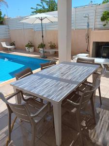 una mesa y sillas en un patio con piscina en Anthorina Villa 20, en Protaras
