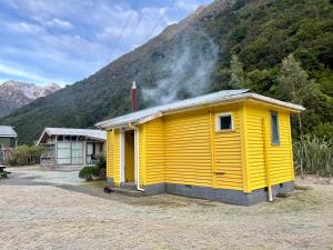 um edifício amarelo em frente a uma montanha em Basic, Super 'Cosy' Cabin in The Middle of National Park and Mountains em Otira