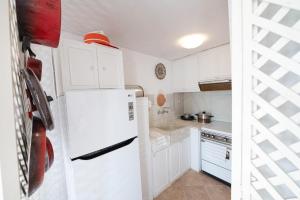 eine Küche mit weißen Schränken und einem weißen Kühlschrank in der Unterkunft Traditional House under the Clock Tower with Sweet View in Poros
