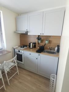 una cocina con armarios blancos y fregadero en Nauji, jaukūs apartamentai, en Klaipėda