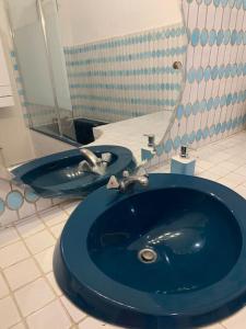 La salle de bains est pourvue d'un lavabo bleu et d'un miroir. dans l'établissement Le Beaufleury et sa terrasse à la Victoire, à Bordeaux