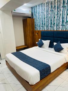 une chambre avec un grand lit et une tête de lit bleue dans l'établissement Hotel Lemon Gota, à Ahmedabad