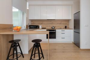 a kitchen with white cabinets and two bar stools at Bright & Stylish Apartment with Balcony 1,5 km to Gdańsk Main City by Renters in Gdańsk