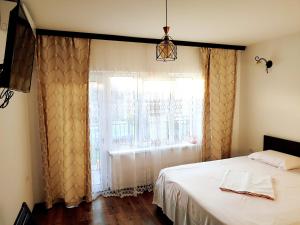 a bedroom with a bed and a window with curtains at Vila Nikol in Năvodari