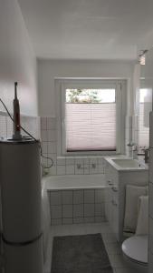 uma casa de banho com uma banheira, um lavatório e uma janela em Wohnung Meeresbrise 48 qm mit Balkon em Rostock