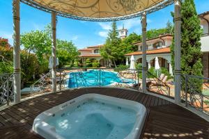 a jacuzzi tub on a deck with a pool at Helena VIP Villas and Suites - Half Board in Sunny Beach